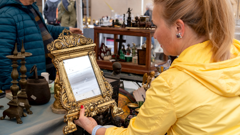 Woman examining a vintage mirror in an antique store