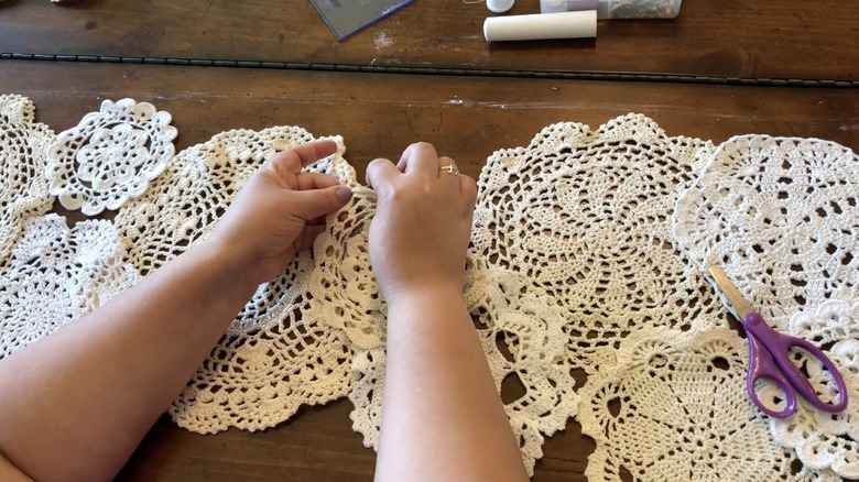 hands sewing doilies together