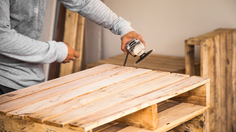 Person DIYing with wooden pallet and saw