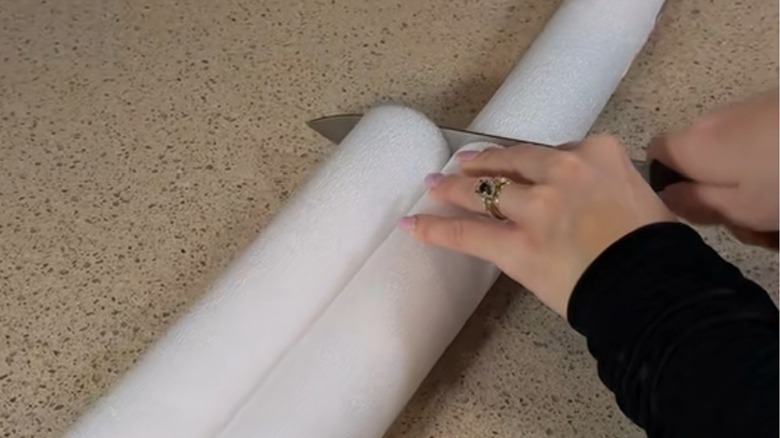 A woman cuts into a white pool noodle