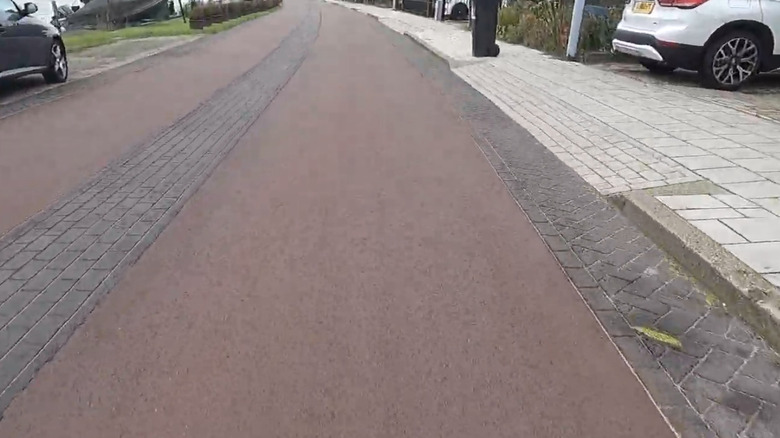 Red asphalt road with black brick