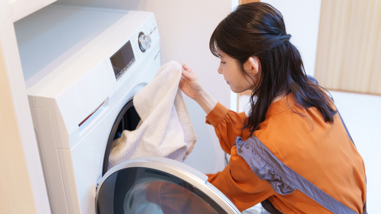 A woman putting clothes into a washing machine