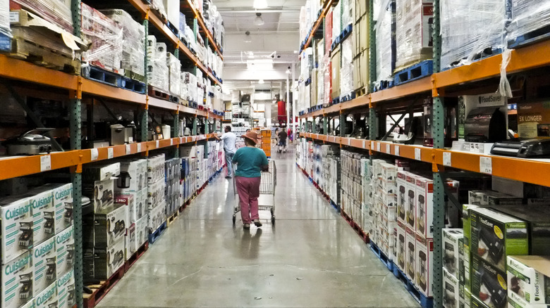 Shopper pushing cart down a Costco aisle
