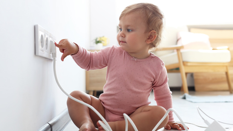 A child plays with the plug of an iron.