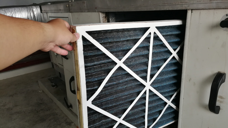 Person checking the air filter in an HVAC unit