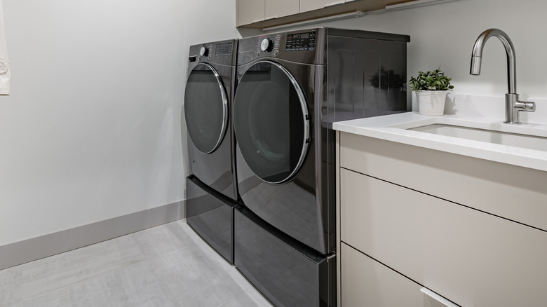 Black front-load washer and dryer set sitting on laundry pedestals