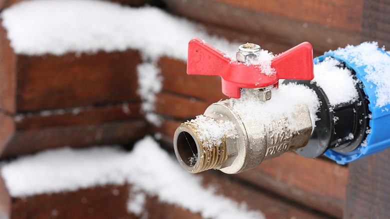 Close up of an outdoor faucet covered with a dusting of snow.