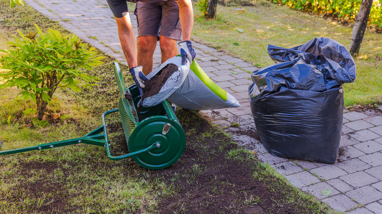 Man filling cart with soil for top dressing lawn