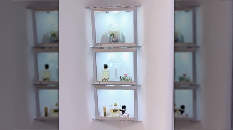 Three chrome picture frames transformed into corner wall storage with glass objects next to a marble wall with shelves of glassware.