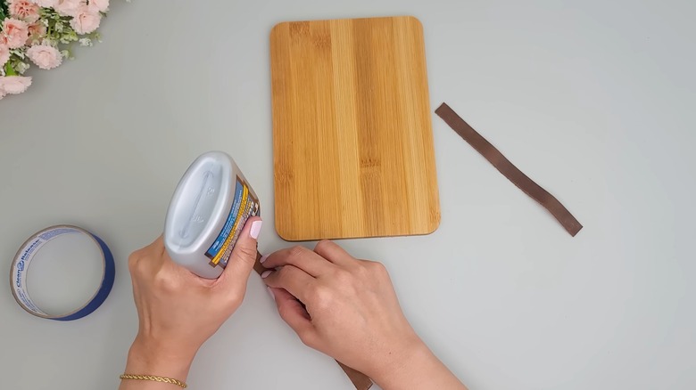 Person upgrading Dollar Tree cutting board with glue and embellishments for a home craft