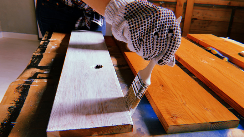 A woman painting a plank for a craft