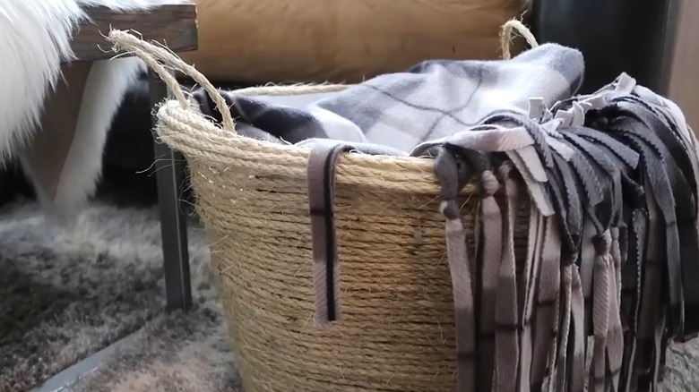An attractive rope blanket basket made from a Dollar Tree plastic basket and jute twine