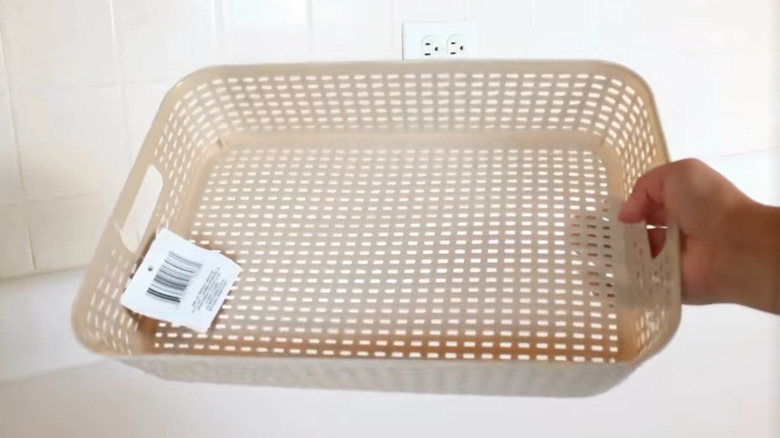 A hand holds a Dollar Tree basket over a kitchen surface