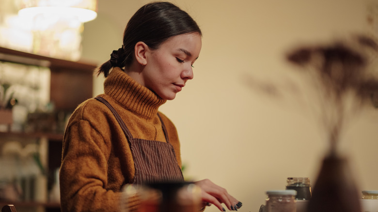 A woman works on a crafts project at a table