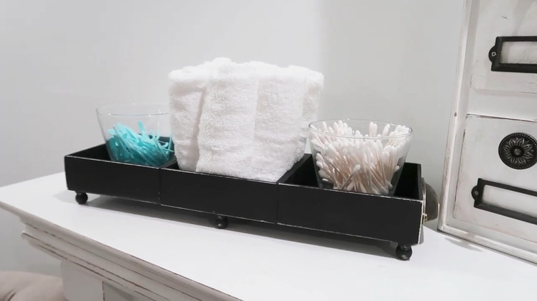 Black DIY tray made from Dollar Tree wood boxes on a bathroom counter holding essentials