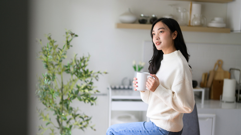 A woman smiles and contemplates in her kitchen