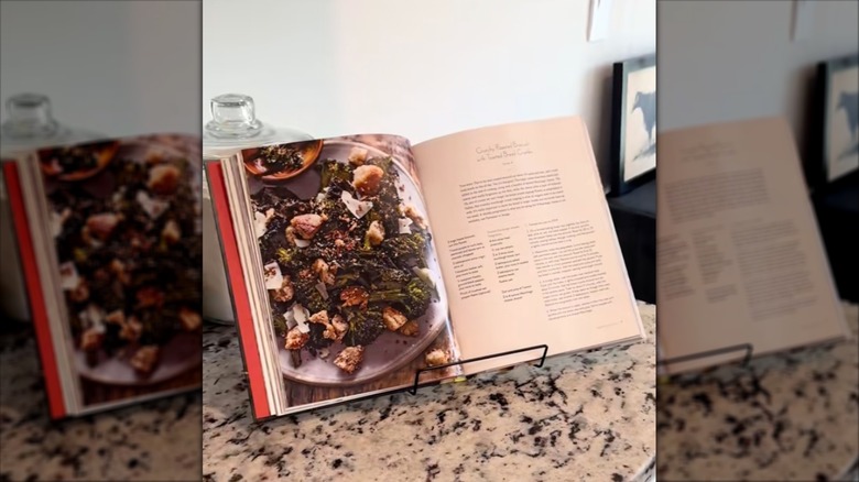 A cookbook stands on a Dollar Tree metal easel on a kitchen counter.