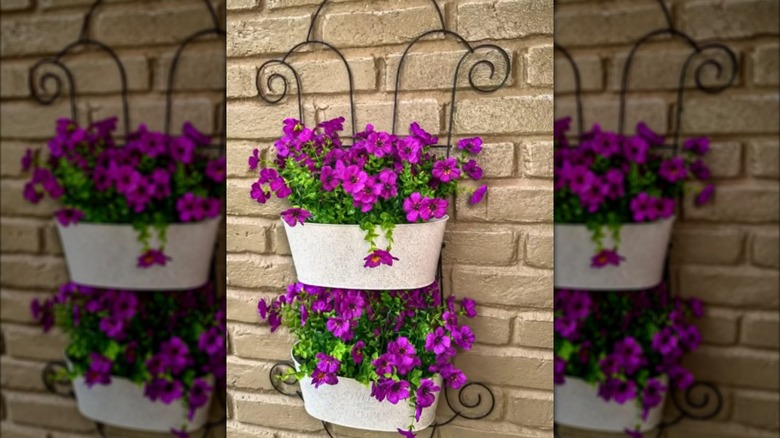 Two Dollar Tree trellises with two metal buckets filled with purple flowers hanging on a wall