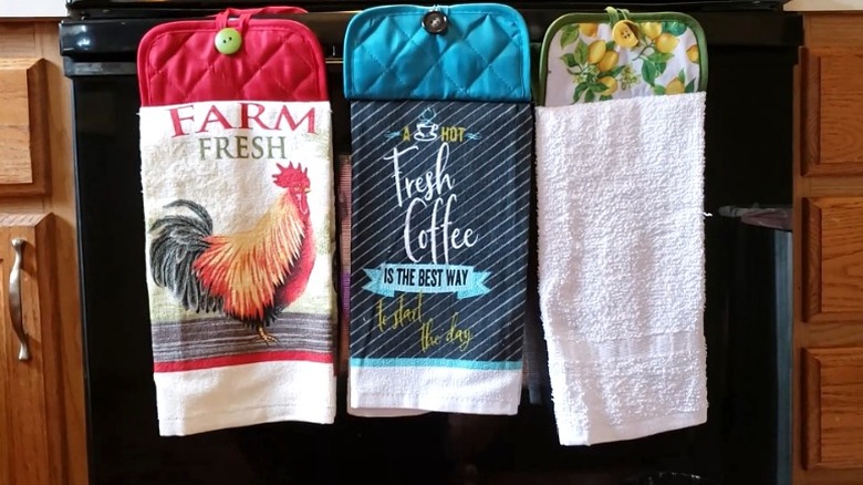 Three DIY hanging kitchen towels made from Dollar Tree supplies on kitchen range