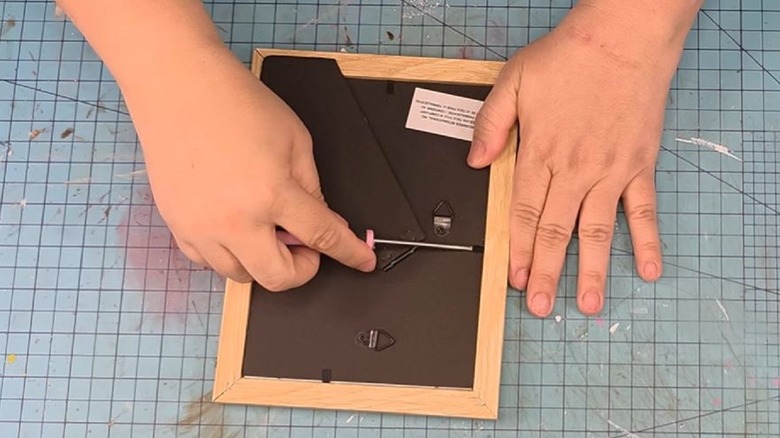 Woman opening up Dollar Tree frame for craft project