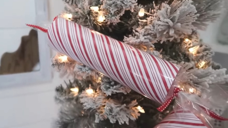 Striped candy cane made from a pool noodle and paper on a tree