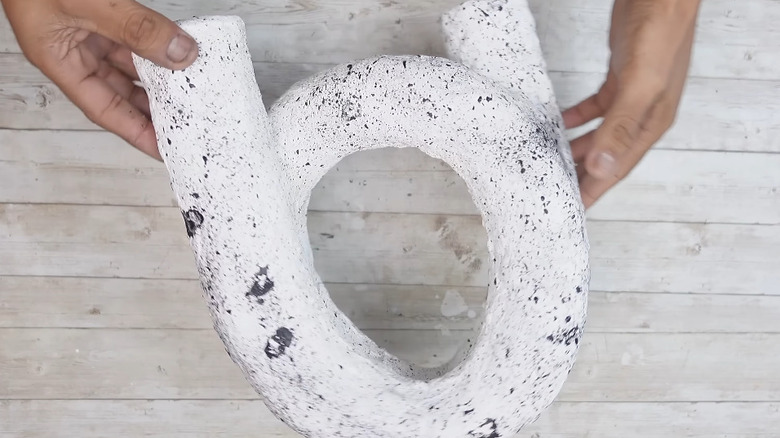 Hands holding an abstract sculpture made from a pool noodle