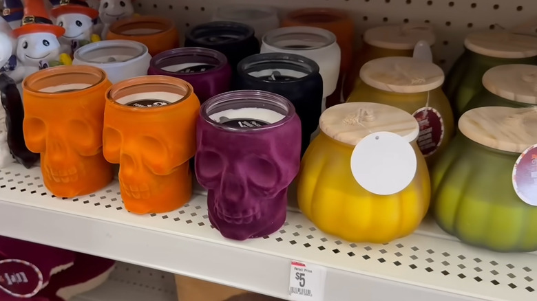 Jewel-toned skulls and glass pumpkin candles sit on a Dollar Tree shelf