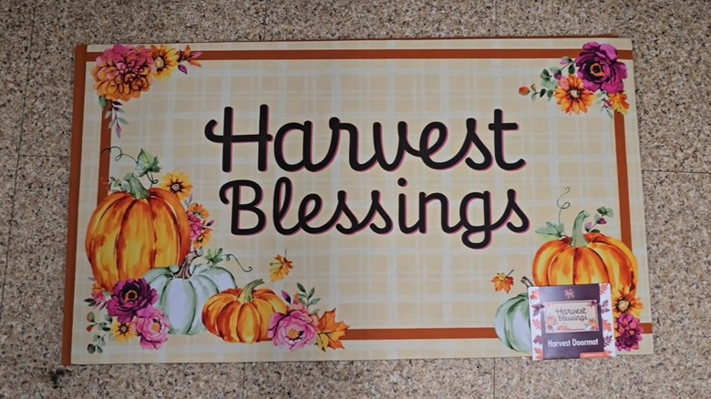 A plaid doormat with pumpkin detail that reads "Harvest Blessings" sits on the floor