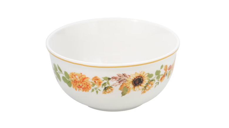 A white bowl with a sunflower printed border and yellow lined rim