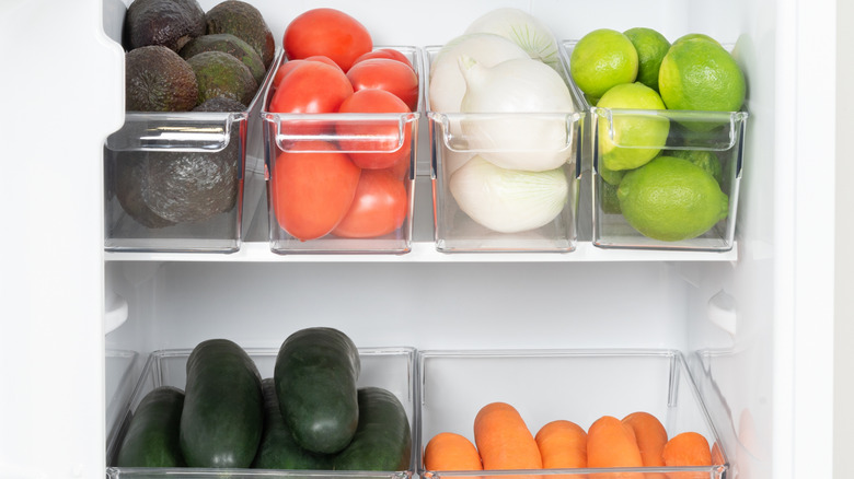 Plastic bins in a fridge with organized fruits and veggies