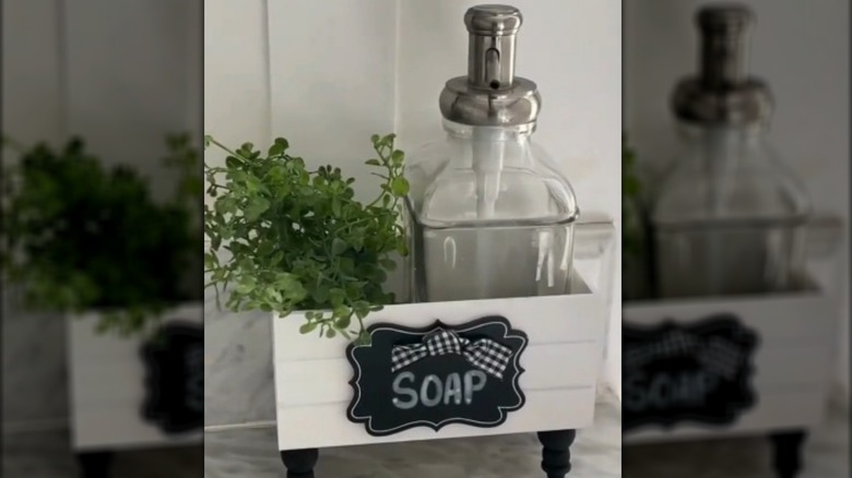 a soap holder crate with ribbon and faux greenery