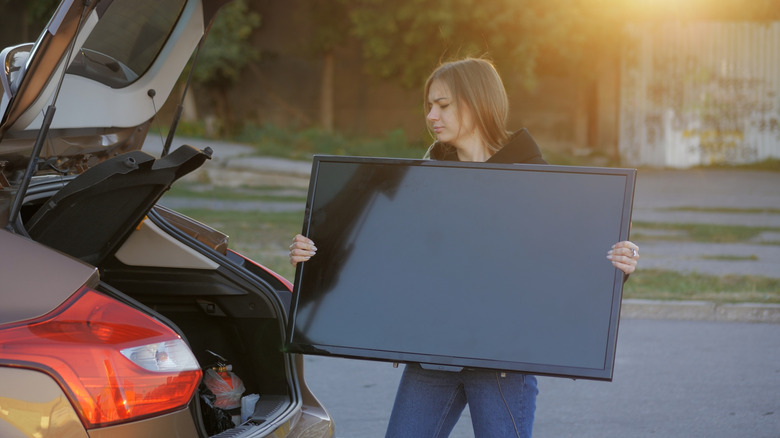 Woman loading her flatscreen TV in her car