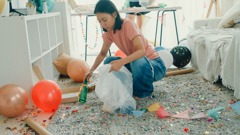 A woman cleans up the floor after a party