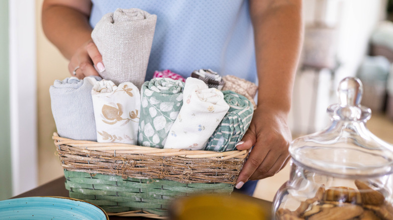 Person holding rolled kitchen towels in basket