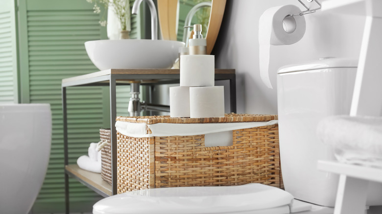 Toilet bowl and rolls of paper in restroom