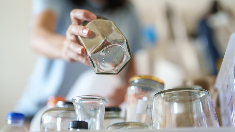 Person sorting empty glass jars of varying shapes and sizes