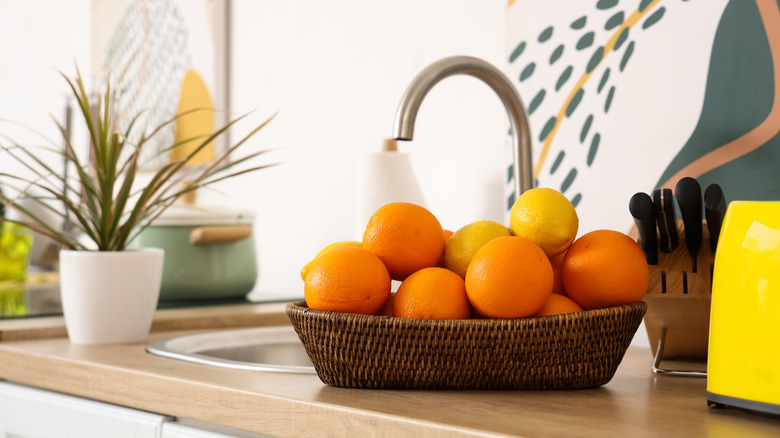 Basket of oranges and lemon beside a sink