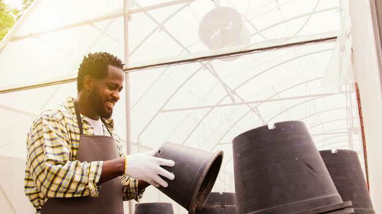 person picking a black planter pot from a stack of pots