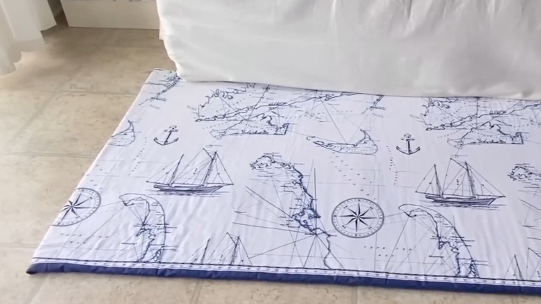 Nautical shower curtain transformed into padded rug over tile floor