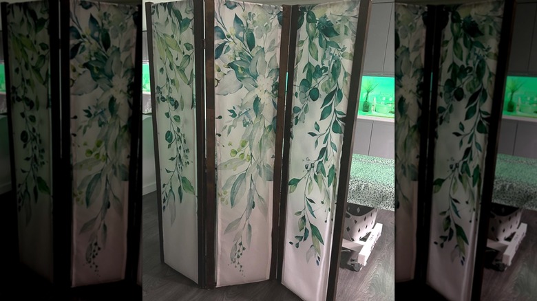 Room divider covered with green and white floral shower curtain in house