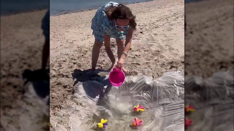 Woman pouring seawater into DIY shower curtain pool at beach