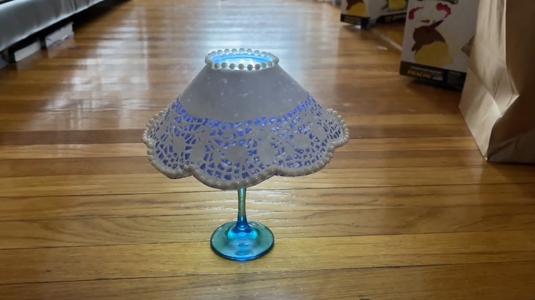 A white lampshade over a painted wine glass