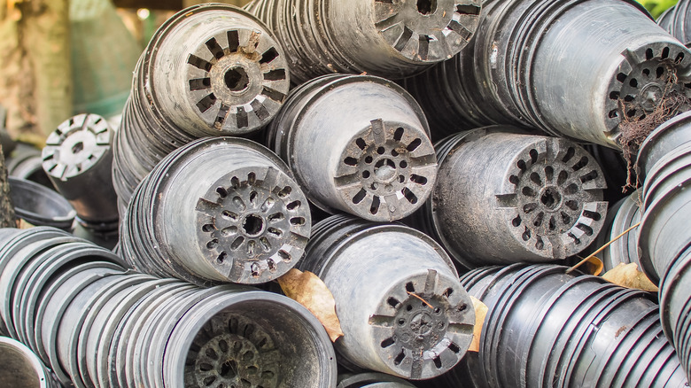 Several stacks of used black nursery pots.