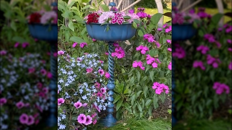 Flower pedestal made from a tall candle holder and a Bundt pan spray painted blue