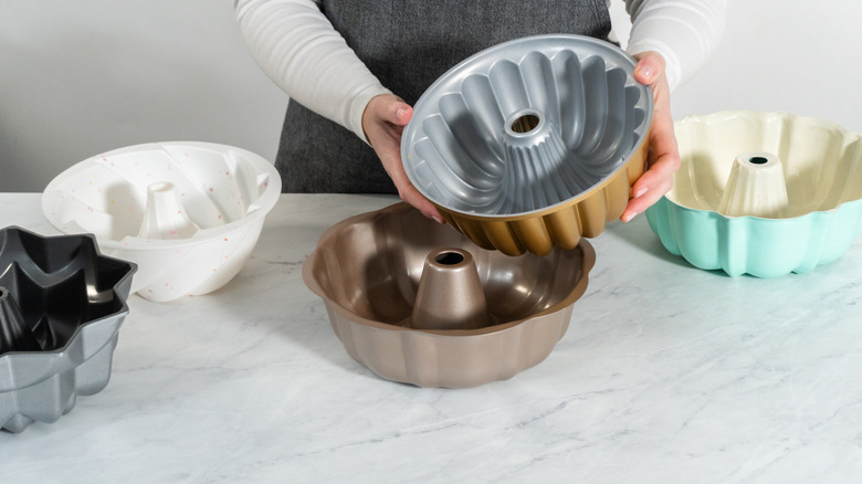 An unidentified woman holding empty bundt pans on a marble surface