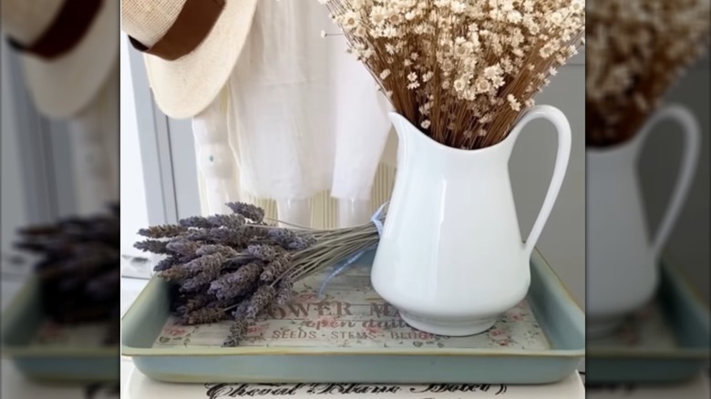 Decorative tray painted light green and made out of a cake pan with a pitcher and dried florals