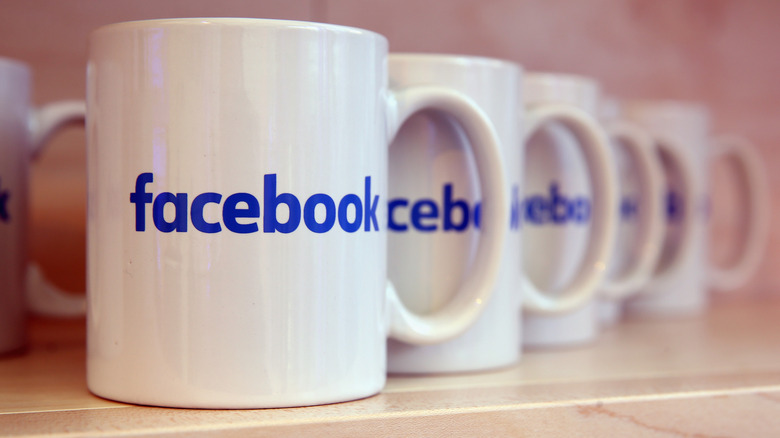 A row of white mugs with blue Facebook logos on them