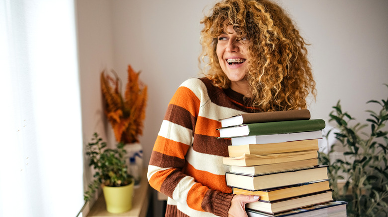 A woman holds a pile of books