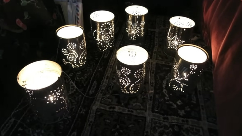 Several soup cans with punched designs sit on the floor