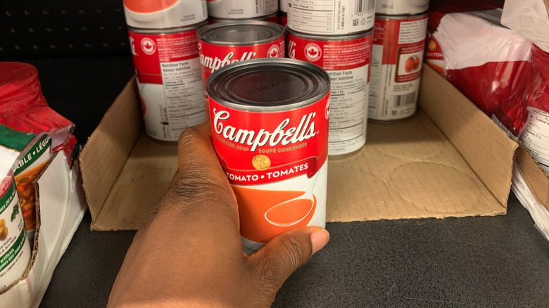 A person takes a soup can off a shelf